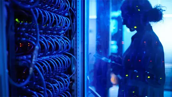 Blue-lit Server Room with Network Engineer in the background