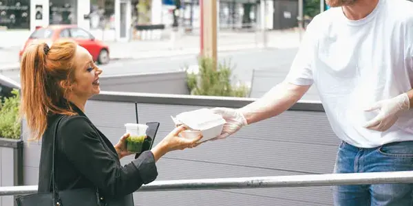 Barista handing a customer takeaway food in a container