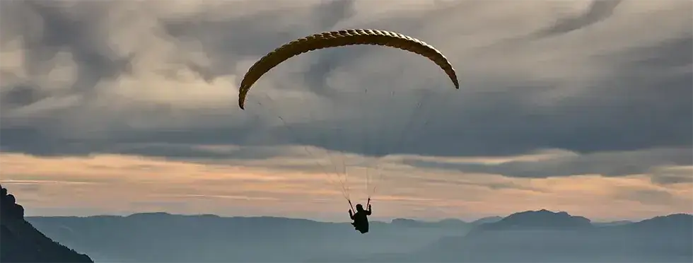 Image of a paraglider against a backdrop of mountains