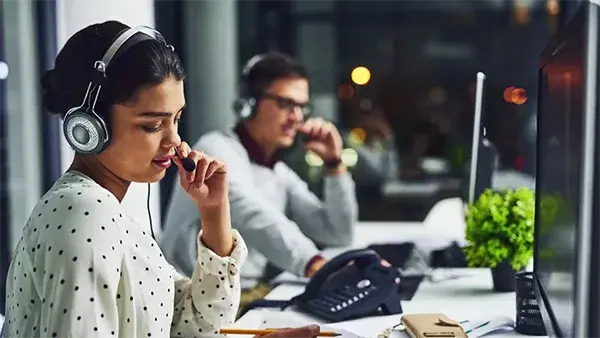 Young woman and man speaking on VoIP headsets in an office environment