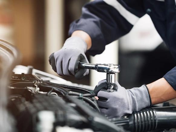 Mechanic operating on car engine with wrench in garage
