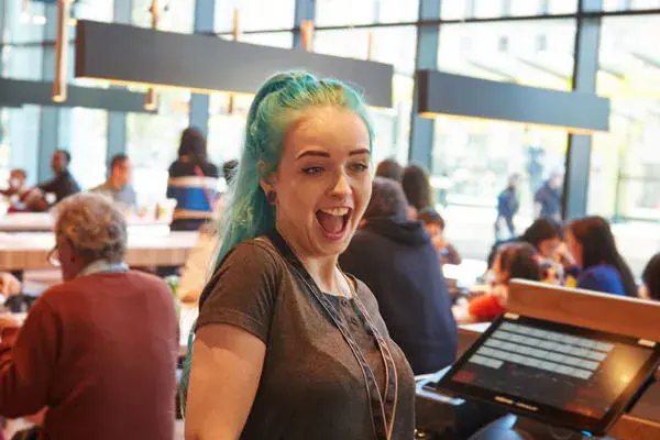 wagamama employee standing next to till laughing and smiling