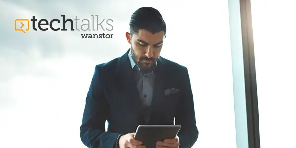 Young businessman leaning against office window using digital tablet device