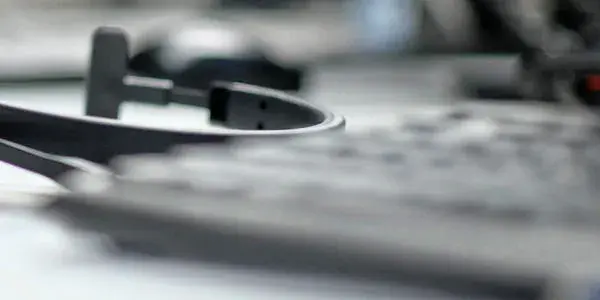 Closeup of headphones behind defocused keyboard on desk