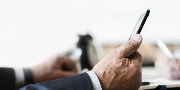 Hand of senior business professional holding mobile device